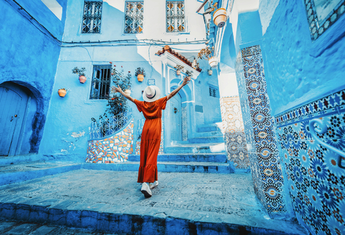 Frau mit rotem Kleid besucht die blaue Stadt Chefchaouen in Marokko