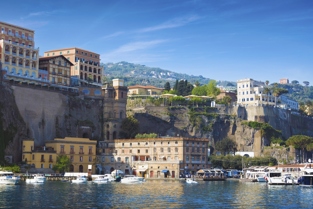 Sorrento, Italien, mit mehrfarbigen Luxushotels auf Klippen über ruhiger Marina mit Booten
