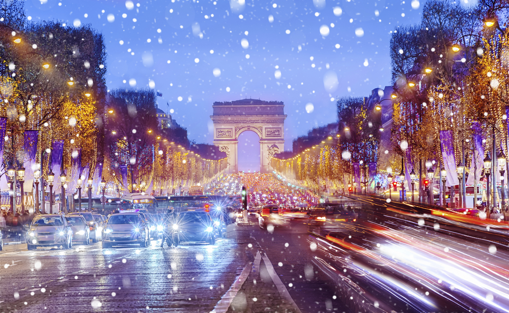 Arc de Triomphe in Paris im Winter mit Schneefall und beleuchteter Champs-Élysées
