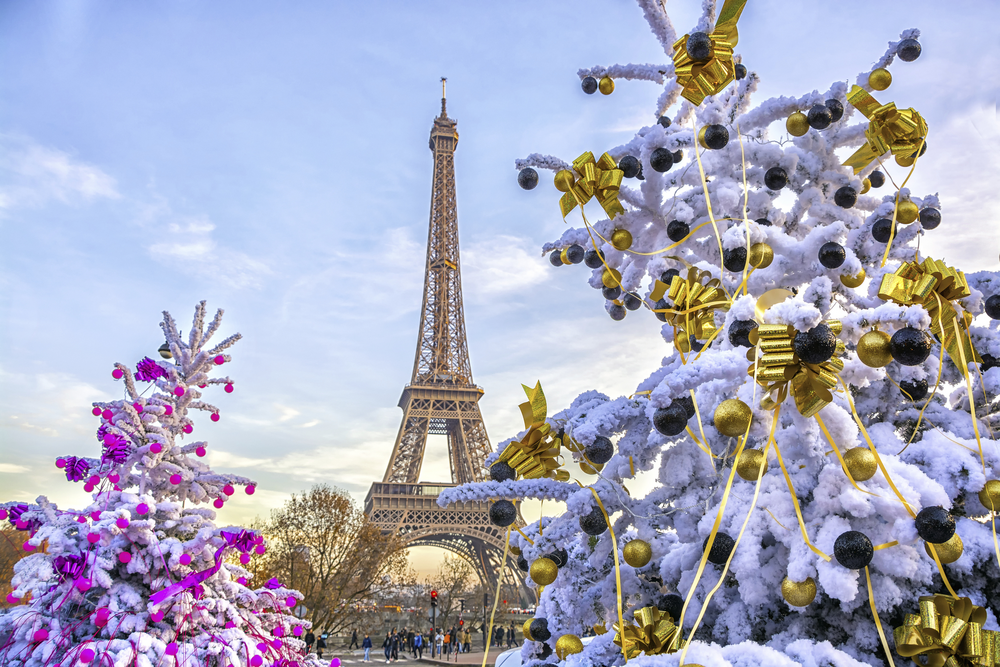Eiffelturm in Paris im Winter mit schneebedeckten, festlich geschmückten Bäumen im Vordergrund