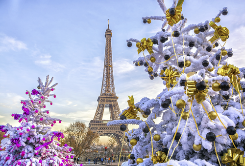 Eiffelturm in Paris im Winter mit schneebedeckten, festlich geschmückten Bäumen im Vordergrund