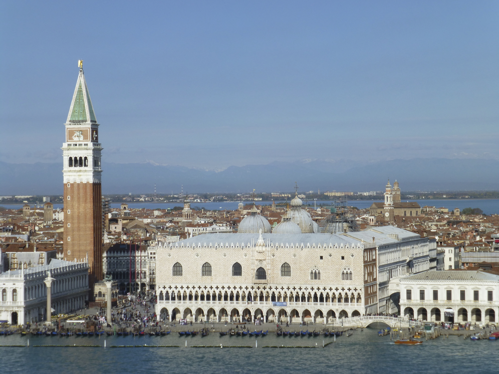 Großer Platz mit langem Gebäude und hohem Turm am Wasser