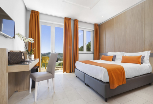 Modernes Hotelzimmer im O Sole Mio in Sant’Agata sui Due Golfi mit Doppelbett, Sitzbereich und großen Fenstern mit Tageslicht