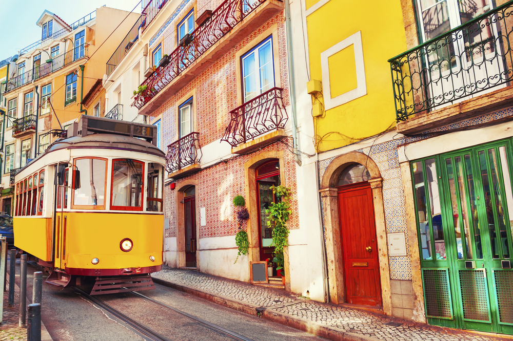 gelbe Straßenbahn in einer bunten Gasse von Lissabon