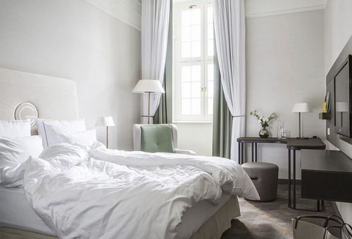 Helles Hotelzimmer mit Doppelbett, Schreibtisch und Fenster im Gewandhaus Dresden.