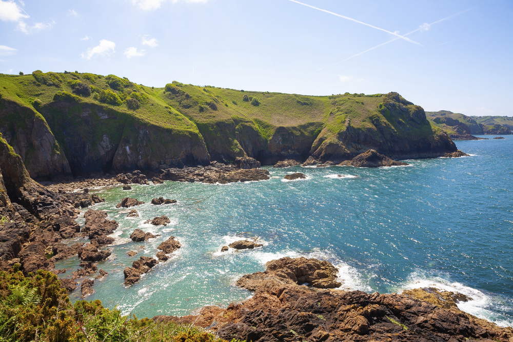Felsige Küste auf Jersey mit grünen Klippen, türkisblauem Meer und kleinen Buchten