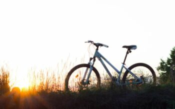 Abgestelltes Fahrrad im Rasen und im Hintergrund der Sonnenuntergang.